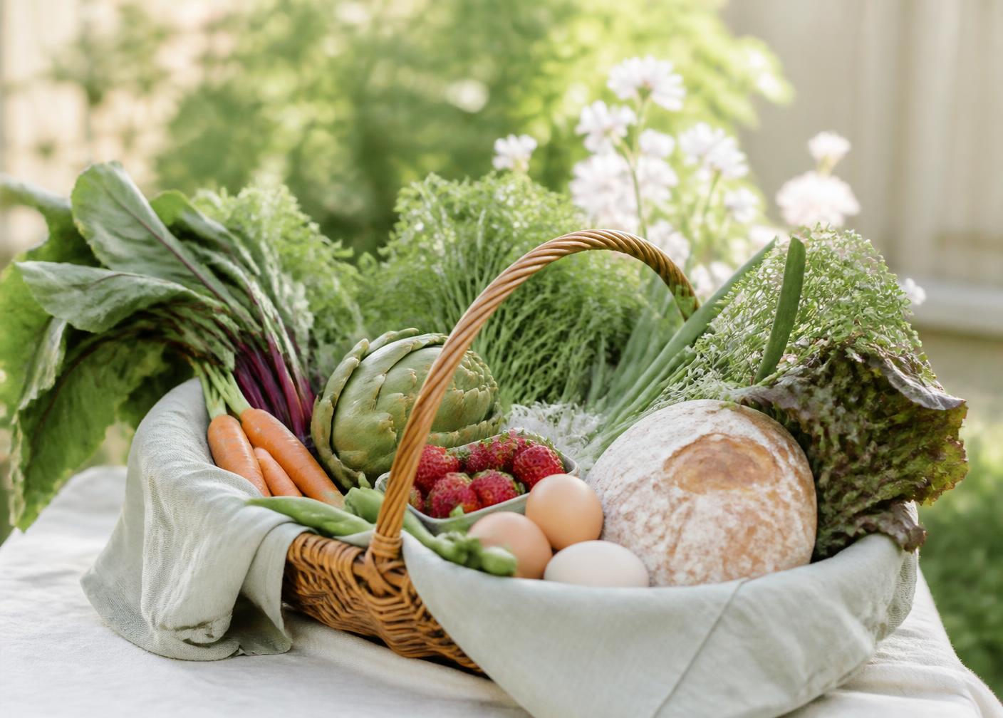 Panier en osier rempli de légumes frais, fraises, œufs fermiers et pain artisanal